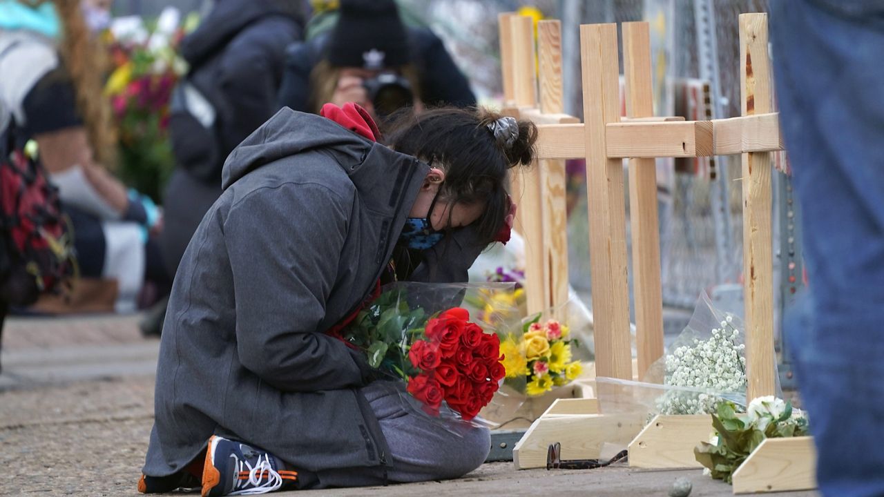 Star Samkus, who works at the King Soopers grocery store and knew three of the victims of a mass shooting at the store a day earlier, cries while kneeling in front of crosses placed in honor of the victims, Tuesday, March 23, 2021, in Boulder, Colo. (AP Photo/David Zalubowski)