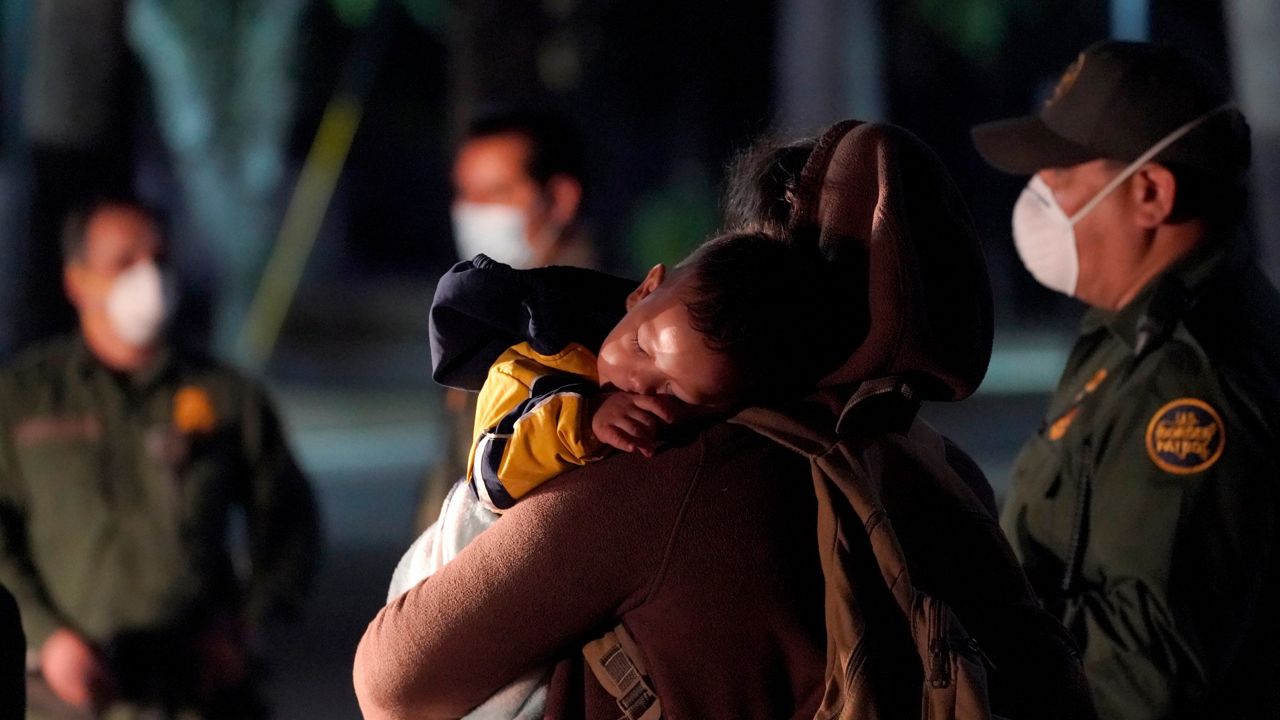 A migrant child sleeps on the shoulder of a woman at an intake area after turning themselves in upon crossing the U.S.-Mexico border, early Wednesday, March 24, 2021, in Roma, Texas. (AP Photo/Julio Cortez)