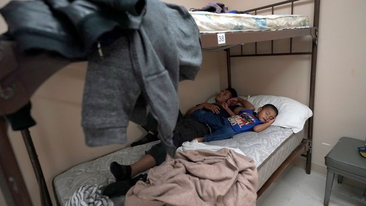 A 4-year-old migrant boy sleeps next to his father at a shelter, Monday, March 22, 2021, in Harlingen, Texas. (AP Photo/Julio Cortez)