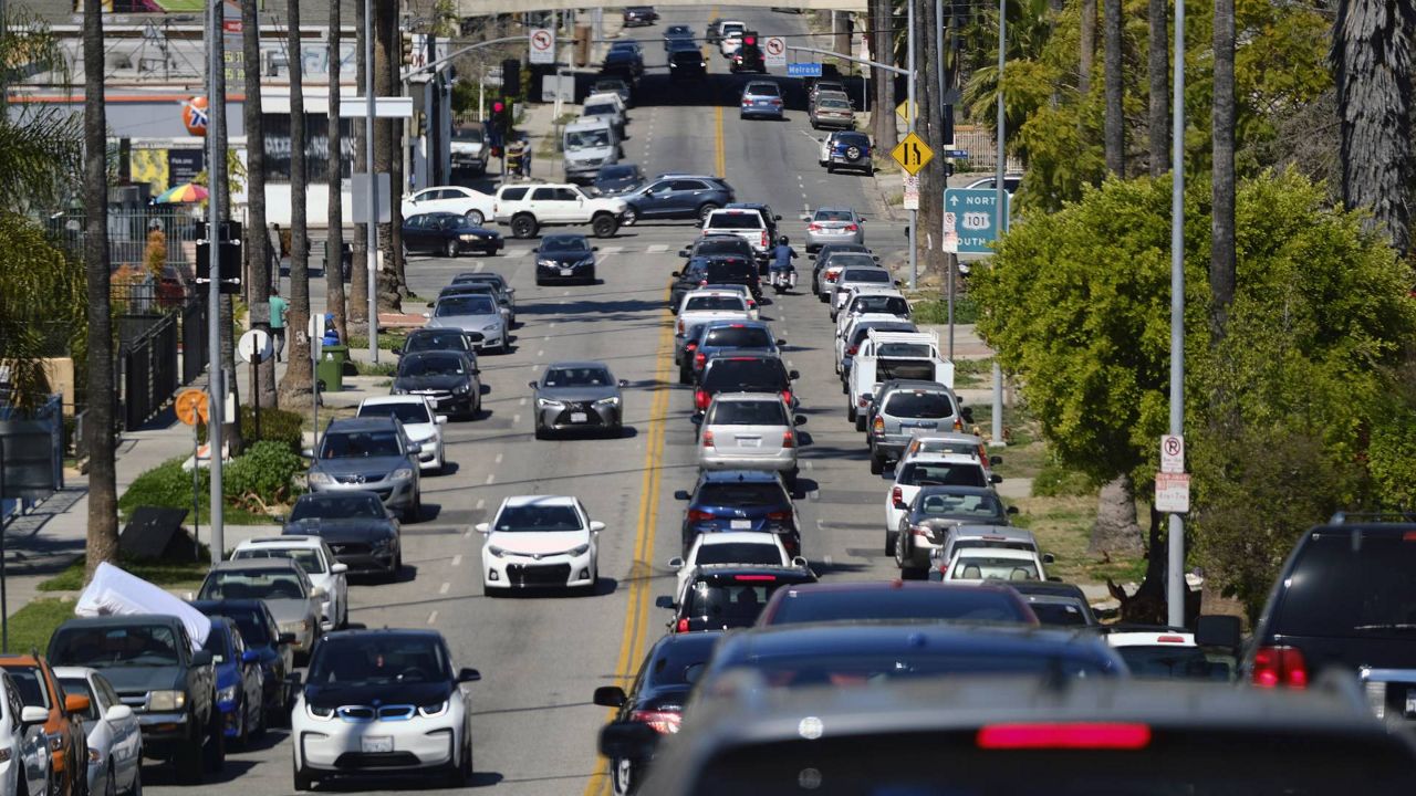 A backed up line of traffic winds its way along a street near downtown Los Angeles on March 28, 2021. (AP Photo/Richard Vogel)