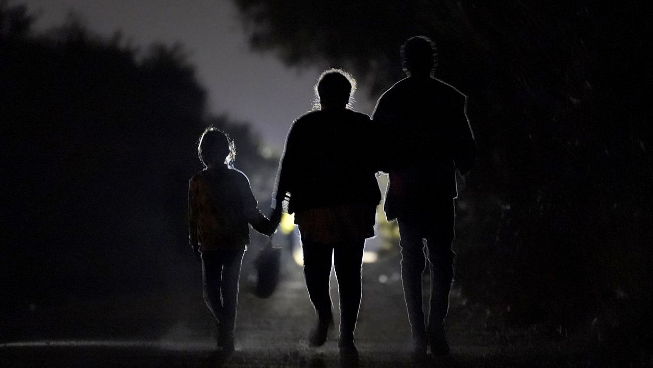 A 7-year-old migrant girl from Honduras, left, walks with Fernanda Solis, 25, center, also of Honduras, and an unidentified man as they approach a U.S. Customs and Border Protection processing center to turn themselves in while seeking asylum moments after crossing the U.S.-Mexico border, Sunday, March 21, 2021, in Mission, Texas. (AP Photo/Julio Cortez)