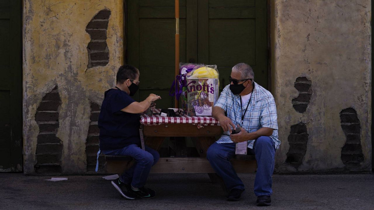 Two visitors rest on a picnic table during the Knott's Taste of Boysenberry Festival at Knott's Berry Farm in Buena Park, Calif., March 30, 2021. (AP Photo/Jae C. Hong)