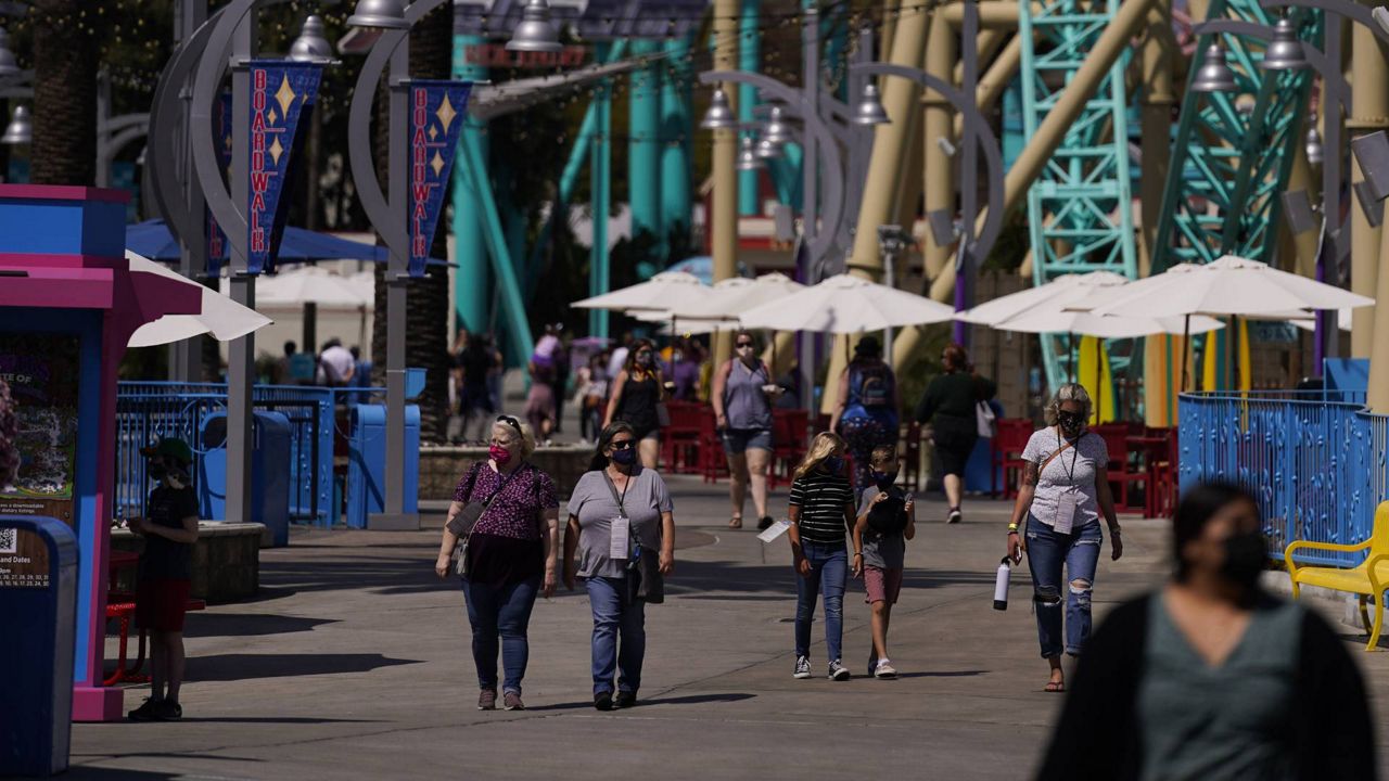 Visitors walk past rides during the Knott's Taste of Boysenberry Festival at Knott's Berry Farm in Buena Park, Calif., March 30, 2021. (AP Photo/Jae C. Hong)