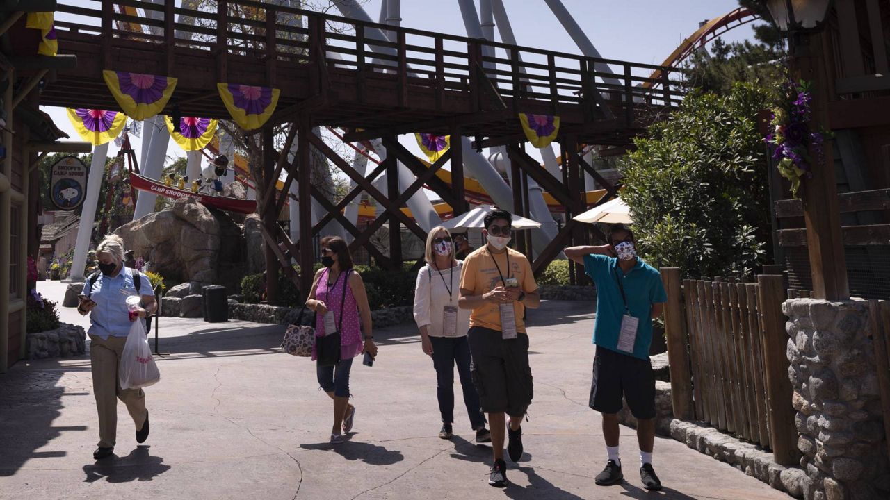 Visitors with face masks attend the Knott's Taste of Boysenberry Festival at Knott's Berry Farm in Buena Park, Calif., Tuesday, March 30, 2021. (AP Photo/Jae C. Hong)
