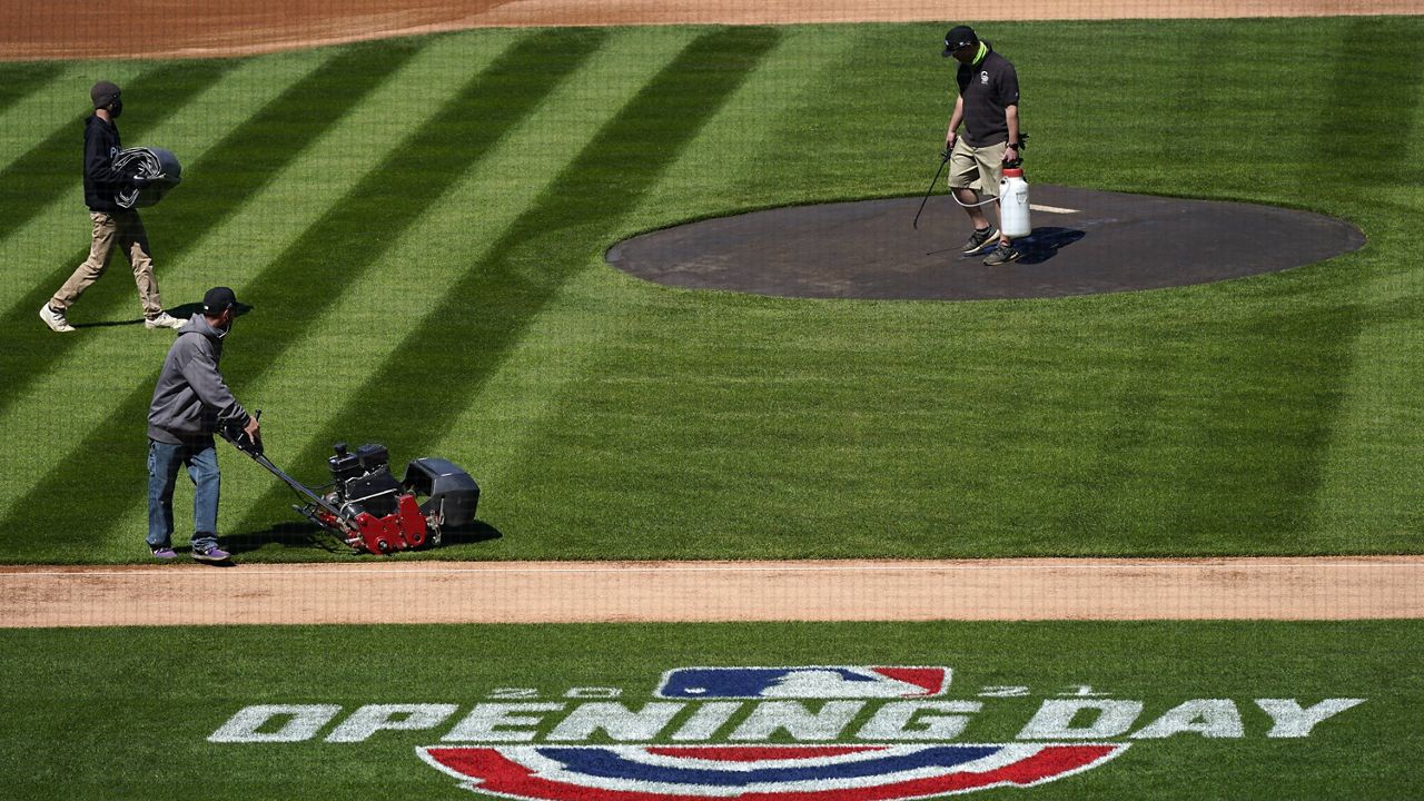 Grounds crew members at Coors Field on Wednesday prepare the surface for the Colorado Rockies to host the Los Angeles Dodgers. (AP Photo/David Zalubowski)