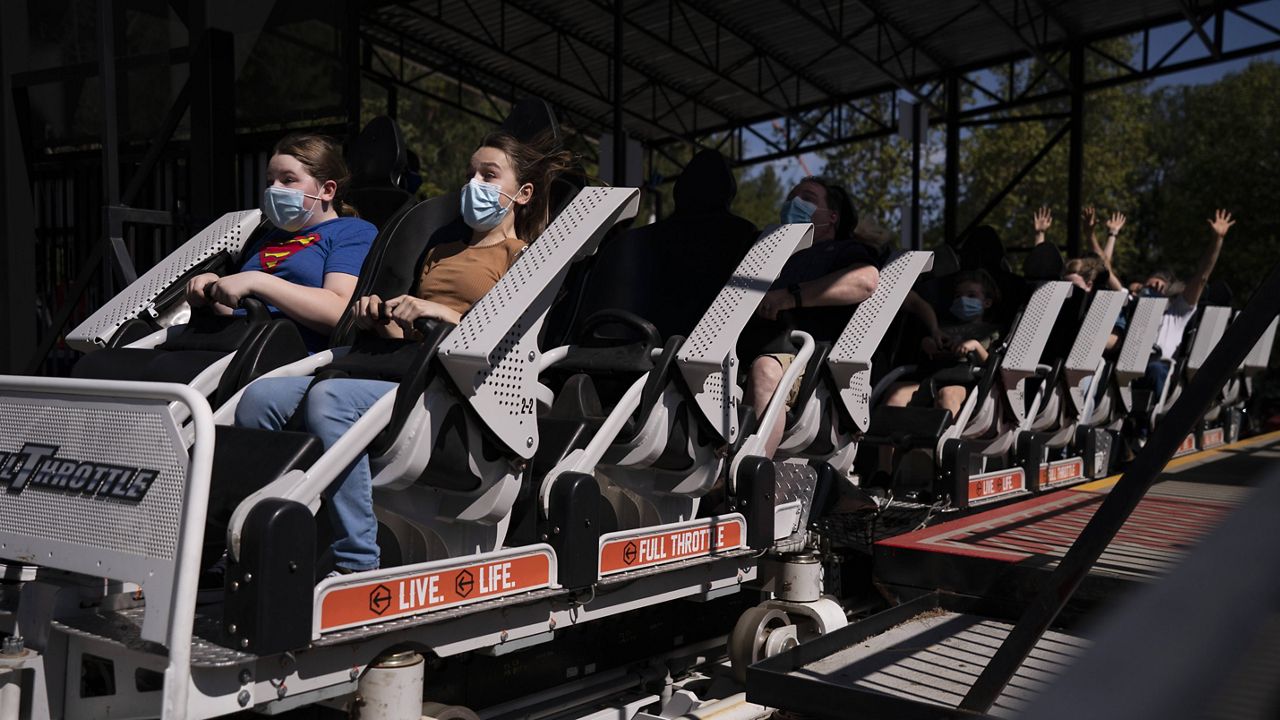Two children wearing face masks react as a roller coaster departs a station at Six Flags Magic Mountain on its first day of reopening to members and pass holders in Valencia, Calif., Thursday, April 1, 2021. (AP Photo/Jae C. Hong)