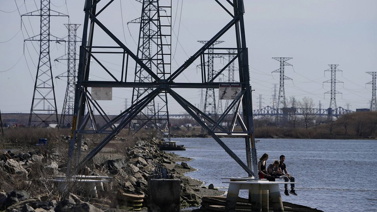 People sit at the base of a transmission tower in North Arlington, N.J., on Tuesday. (AP Photo/Seth Wenig)