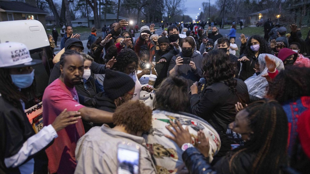 Family and friends, foreground, of Daunte Wright, 20, mourn Sunday, April 11, 2021, in Brooklyn Center, Minn. Wright's family told a crowd that he was shot by police Sunday before getting back into his car and driving away, then crashing the vehicle several blocks away. (AP Photo/Christian Monterrosa)