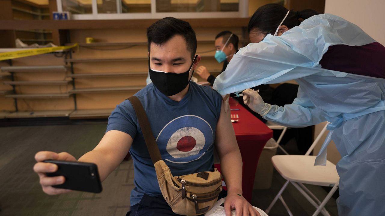 Freeson Wong, 31, takes a selfie as he receives a dose of the Moderna vaccine at a vaccination center in the Chinatown neighborhood of Los Angeles, Monday, April 12, 2021. (AP Photo/Jae C. Hong)