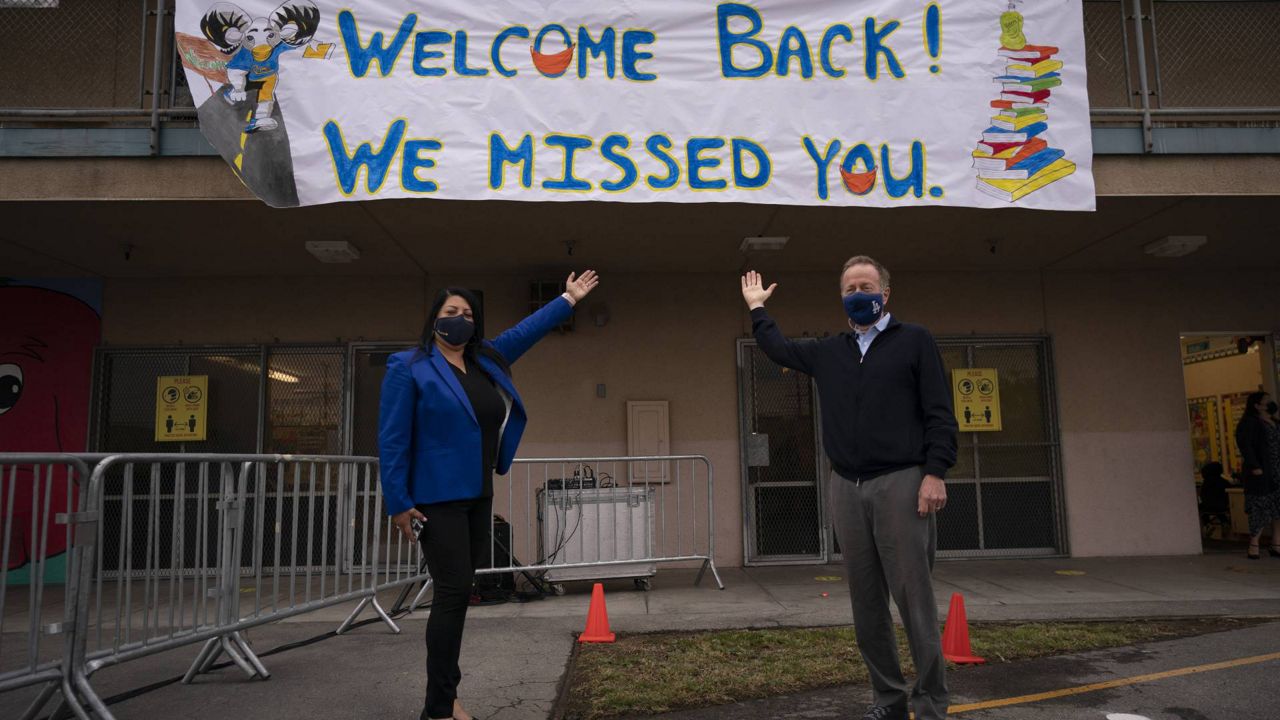 LAUSD Superintendent Austin Beutner and Gabriela Rodriguez, principal of Heliotrope Avenue Elementary School, pose for photos on the first day of in-person learning in Maywood, Calif., Tuesday, April 13, 2021. (AP Photo/Jae C. Hong)
