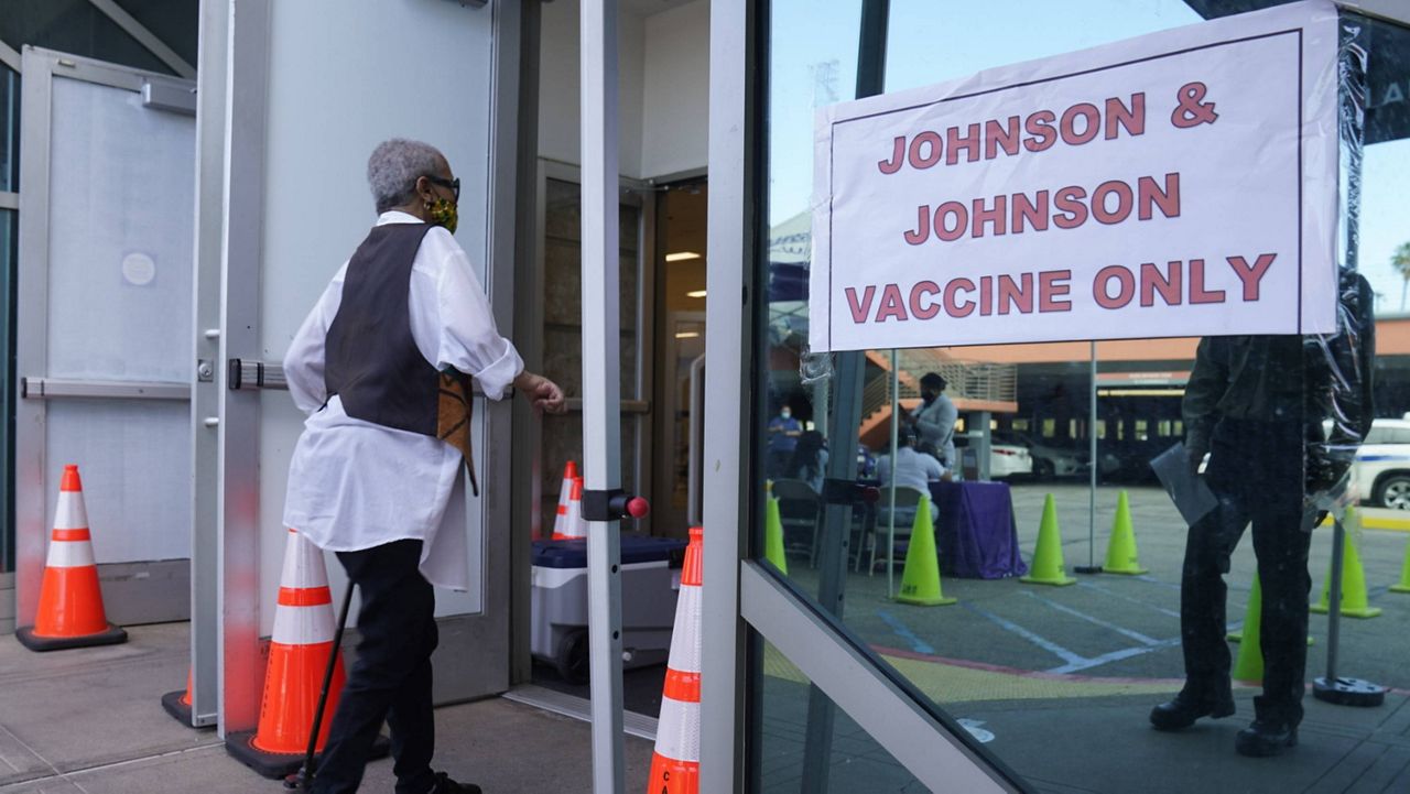 In this April 1, 2021, file photo, people walk in to get their COVID-19 vaccine at the Baldwin Hills Crenshaw Plaza past a sign that says "Johnson & Johnson vaccine only" in Los Angeles. (AP Photo/Damian Dovarganes)