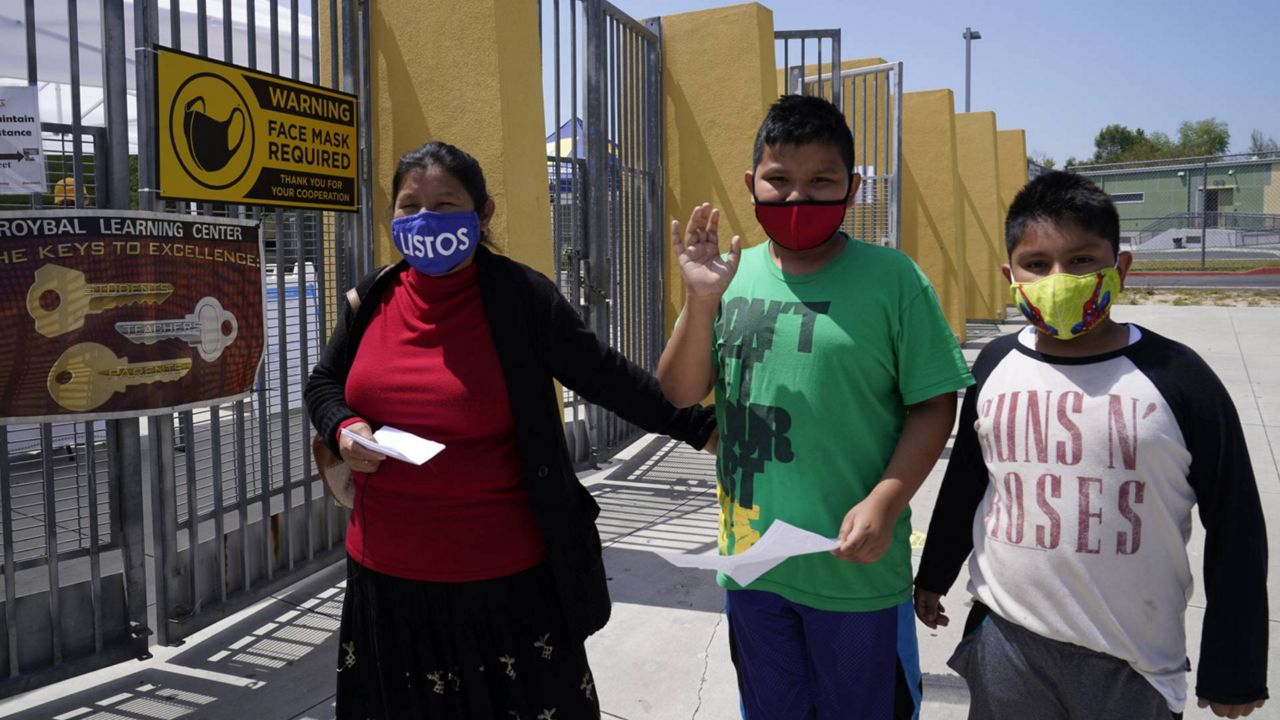 Parent Maria Hernandez, with her sons Edwin Gomez, 10, and Jesus Gomez, 9, arrive to get tested at a COVID-19 testing and vaccination site at the Roybal Learning Center in LA, Thursday, April 15, 2021. (AP Photo/Damian Dovarganes)
