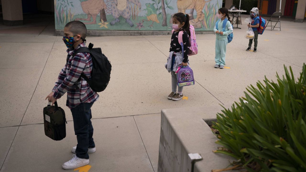 Socially distanced kindergarten students wait for their parents to pick them up on the first day of in-person learning at Maurice Sendak Elementary School in LA, April 13, 2021. (AP Photo/Jae C. Hong)
