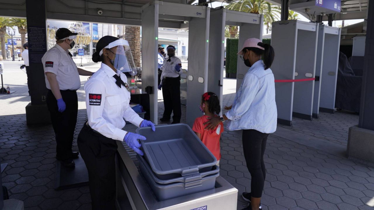 All patrons are screened with walk-through metal detectors as they enter Universal Studios Hollywood officially reopening to the public at 25% capacity with COVID-19 protocols, Friday, April 16, 2021. (AP Photo/Damian Dovarganes)