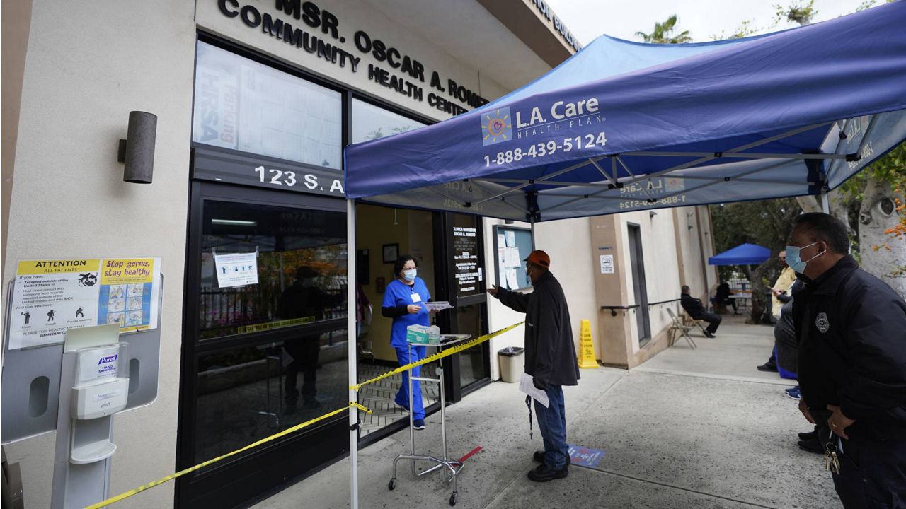 People are screened outdoors as they wait in line to be inoculated with a COVID-19 vaccine at Clinica Monseñor Oscar A. Romero in Los Angeles, April 21, 2021. (AP Photo/Damian Dovarganes)