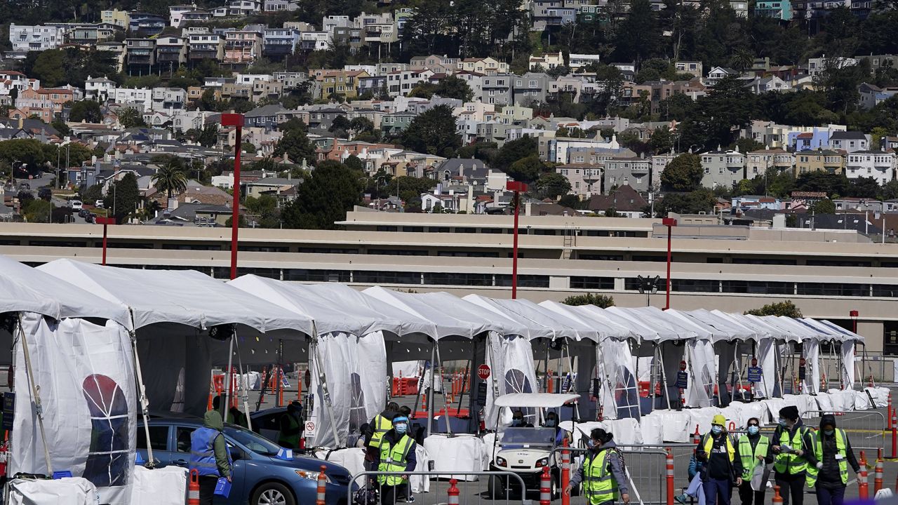 Healthcare workers tend to people in cars at a drive up vaccination center at City College of San Francisco during the coronavirus pandemic in San Francisco on March 25, 2021. (AP Photo/Jeff Chiu)