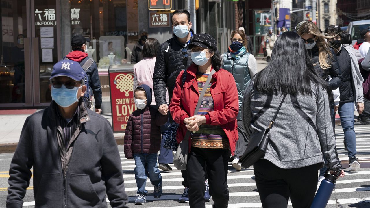 People walk on the street in New York on April 26. (AP Photo/Mark Lennihan)