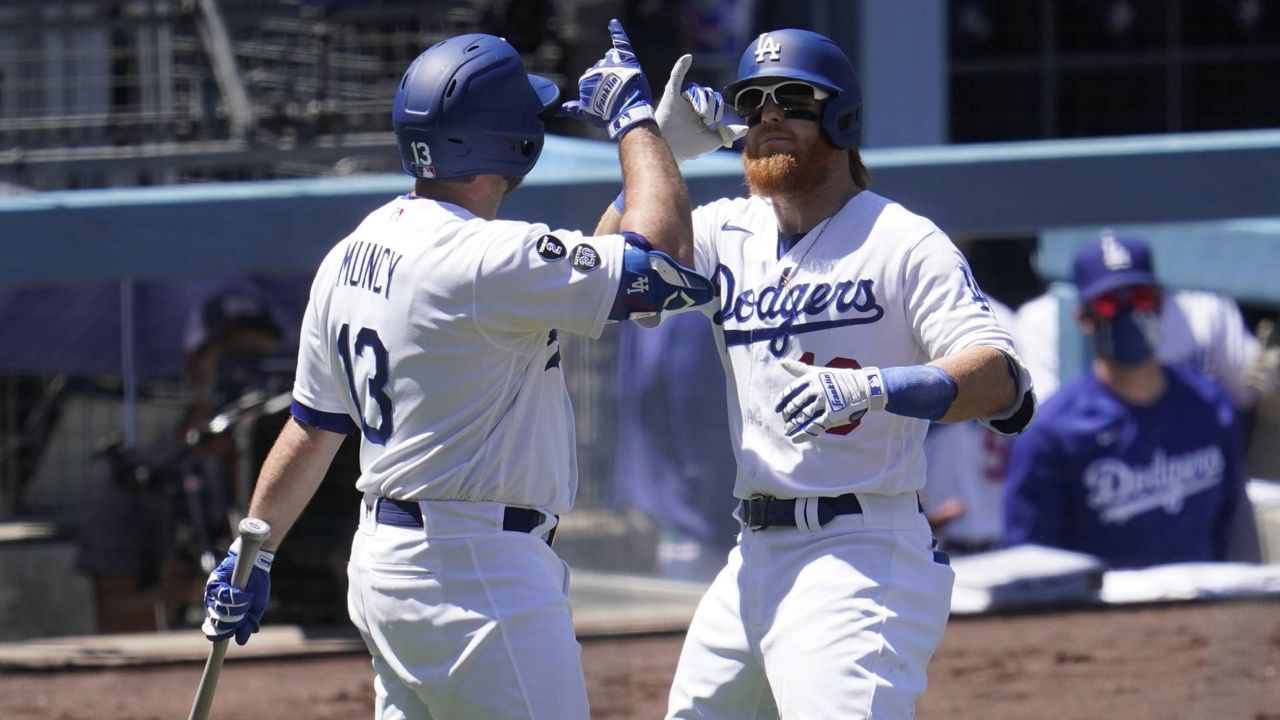 Dodgers' Justin Turner, right, celebrates his solo home run with Max Muncy during the third inning of a baseball game against the Cincinnati Reds Wednesday, April 28, 2021, in Los Angeles. (AP Photo/Marcio Jose Sanchez)