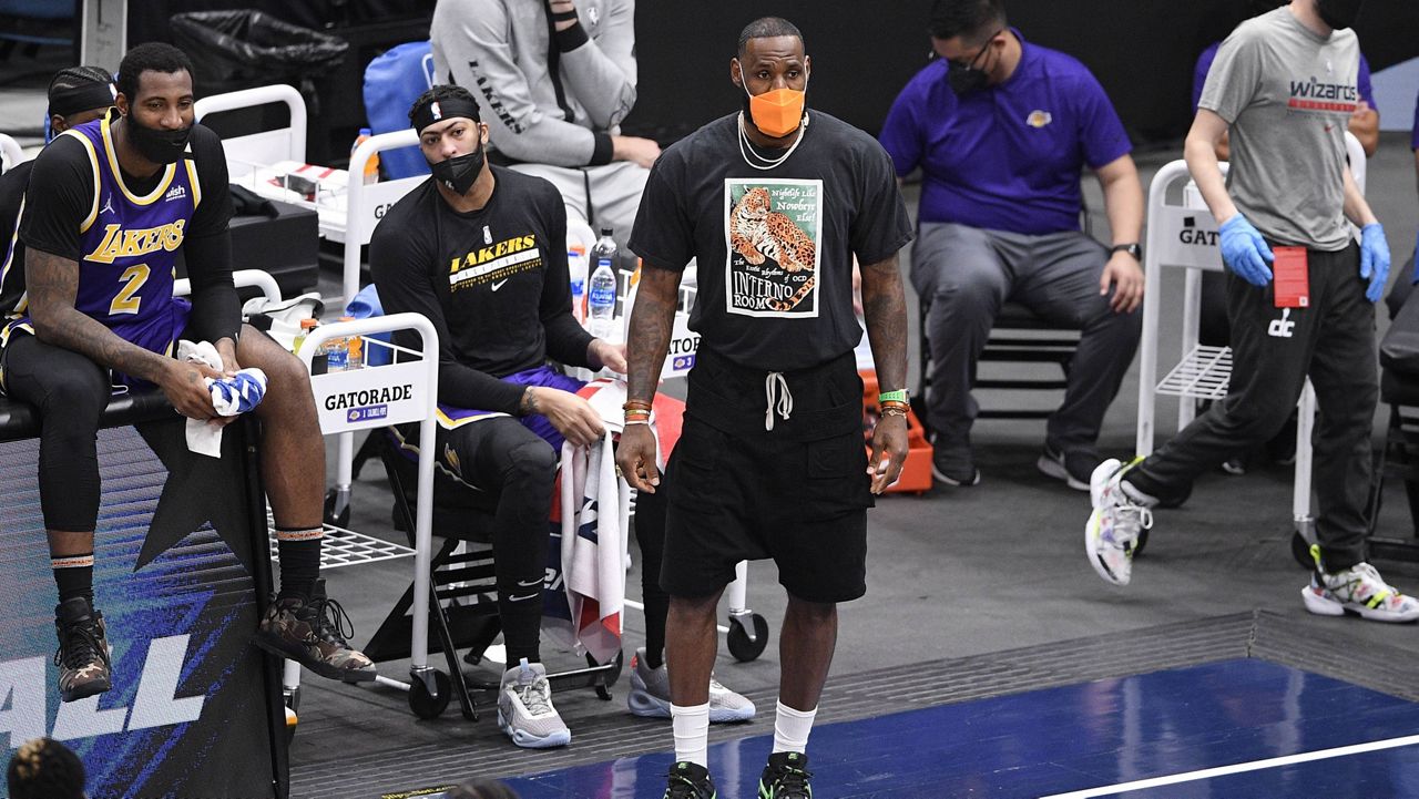 Los Angeles Lakers forward LeBron James, in orange mask, watches during the first half of an NBA basketball game against the Washington Wizards, Wednesday, April 28, 2021, in Washington. (AP Photo/Nick Wass)