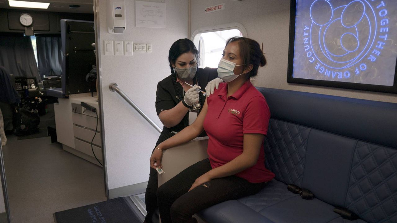 Nurse Natasha Garcia administers a dose of the Moderna COVID-19 vaccine to Magaly Esparza in a mobile clinic set up in the parking lot of a shopping center in Orange, Calif., April 29, 2021. (AP Photo/Jae C. Hong)