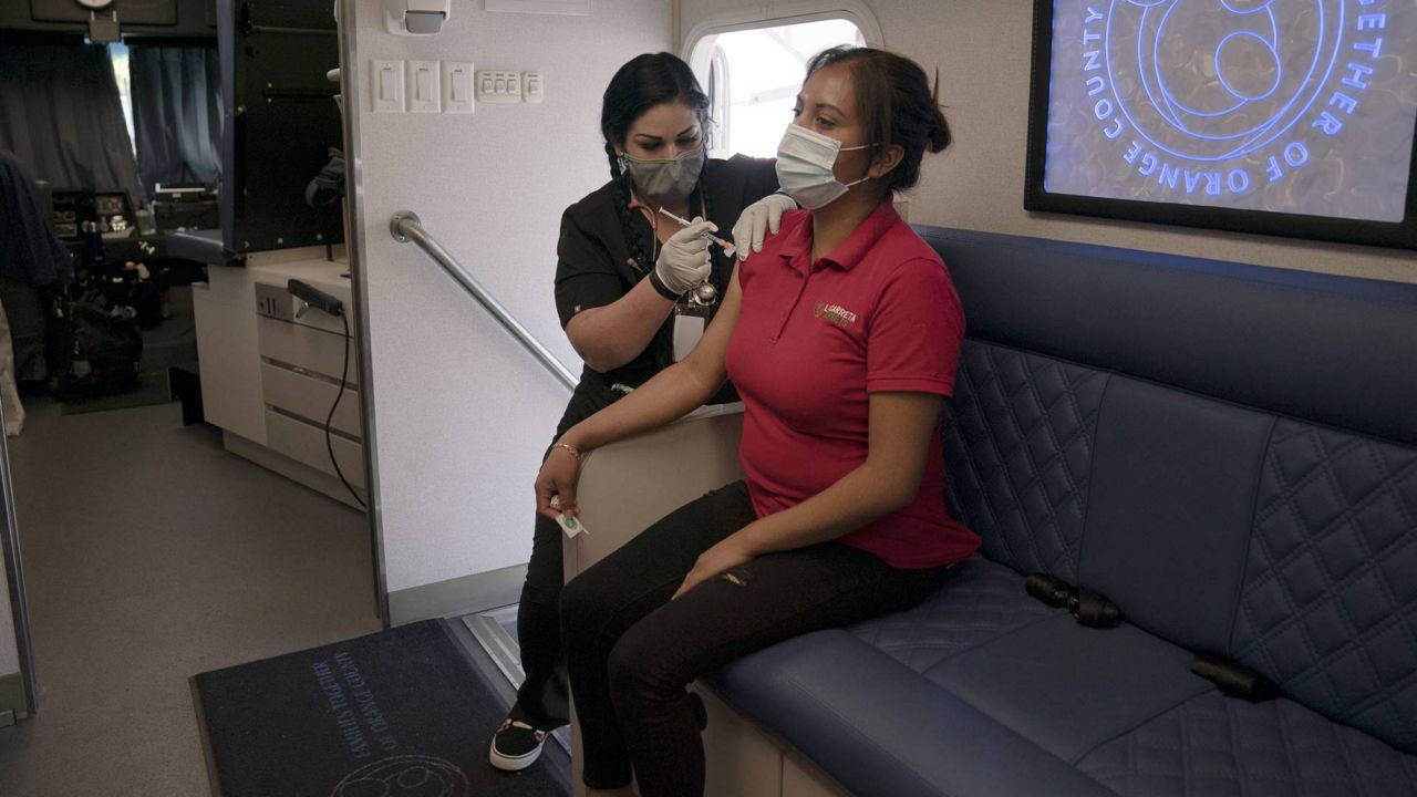 Nurse Natasha Garcia administers a dose of the Moderna COVID-19 vaccine to Magaly Esparza in a mobile clinic set up in the parking lot of a shopping center in Orange, Calif., April 29, 2021. (AP Photo/Jae C. Hong)