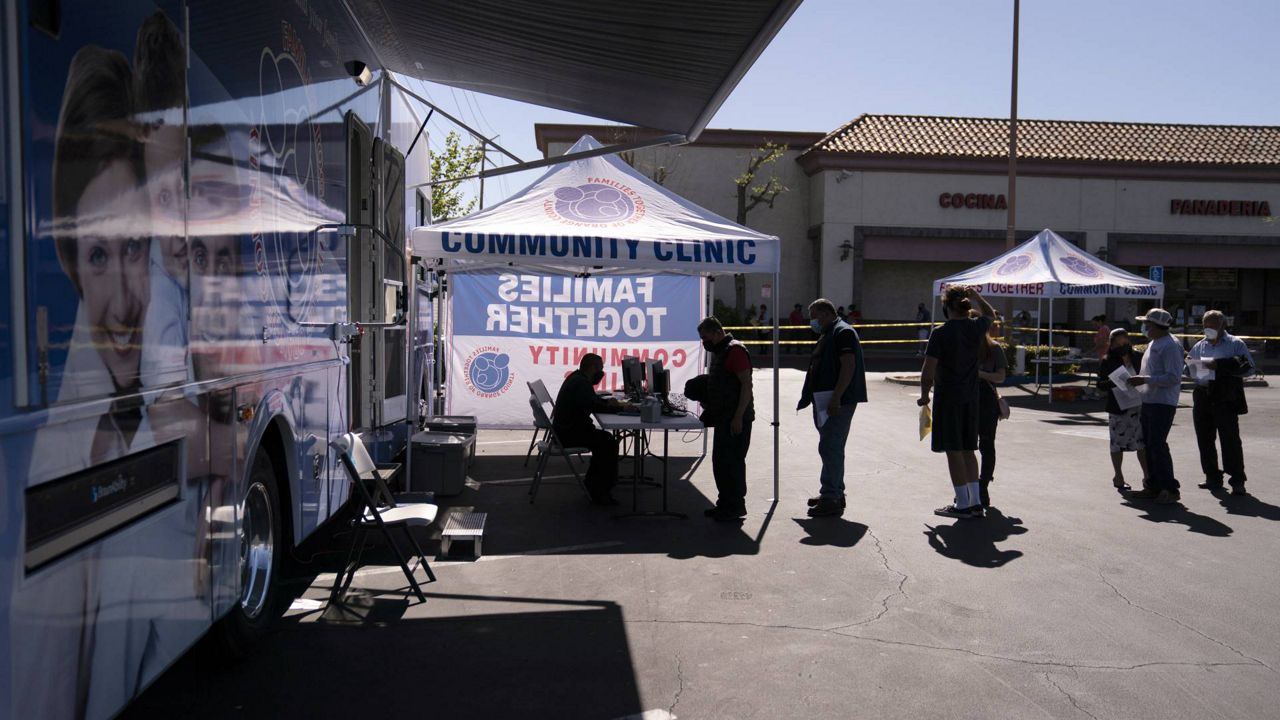 People check in to receive the Moderna COVID-19 vaccine at a mobile clinic set up in the parking lot of a shopping center in Orange, Calif., April 29, 2021. (AP Photo/Jae C. Hong)