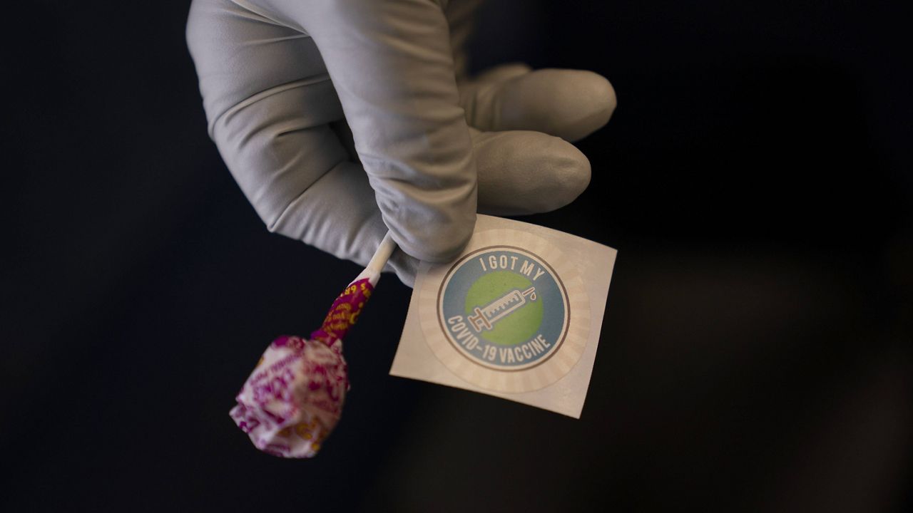 Nurse Natasha Garcia prepares a lollipop and an "I Got My COVID-19 Vaccine" sticker for a recipient in a mobile clinic set up in the parking lot of a shopping center in Orange, Calif., Thursday, April 29, 2021.