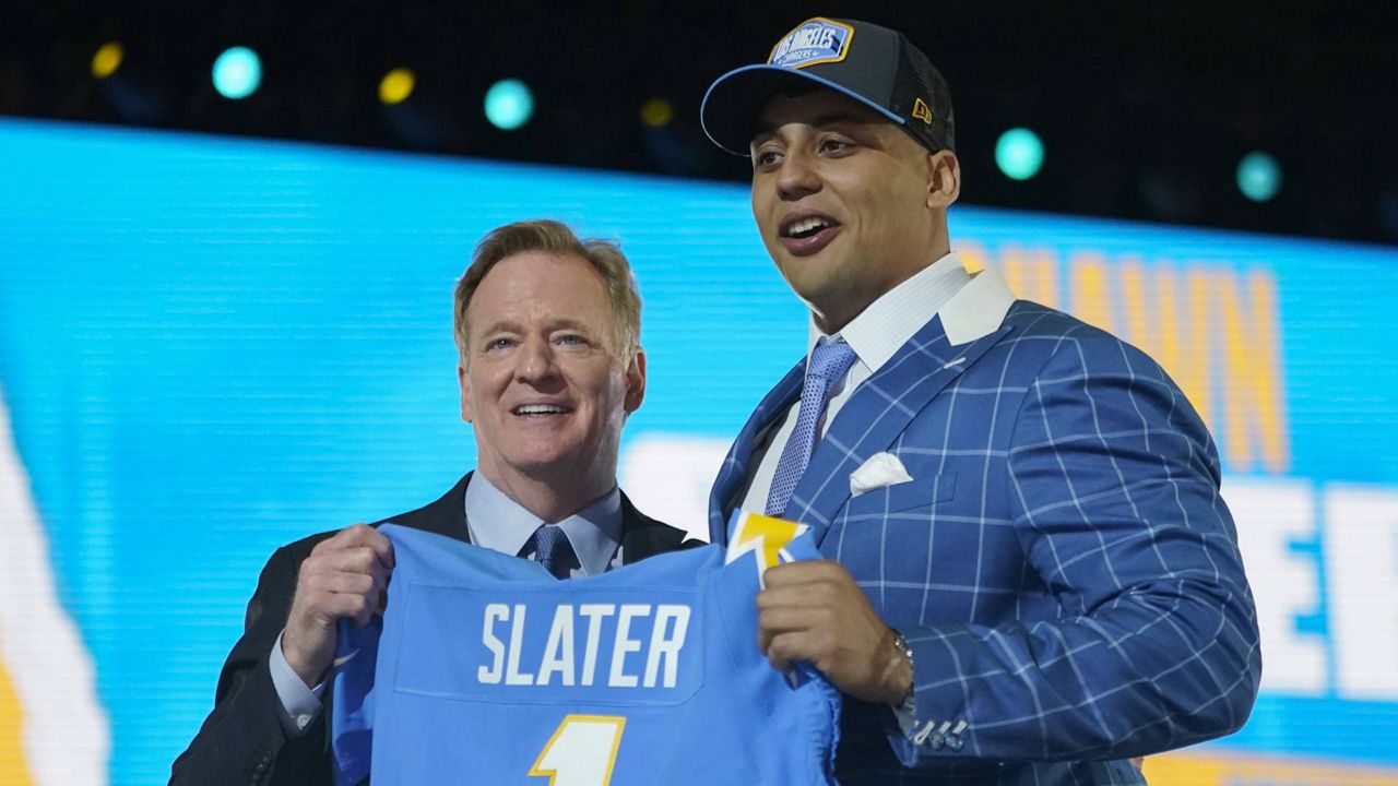 Northwestern tackle Rashawn Slater holds a team jersey with NFL Commissioner Roger Goodell after the Chargers selected him with the 13th pick in the NFL draft Thursday April 29, 2021, in Cleveland. (AP Photo/Tony Dejak)