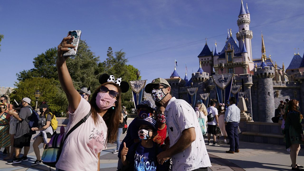 A family takes a photo in front of Sleeping Beauty's Castle at Disneyland in Anaheim, Calif., Friday, April 30, 2021. (AP Photo/Jae Hong)