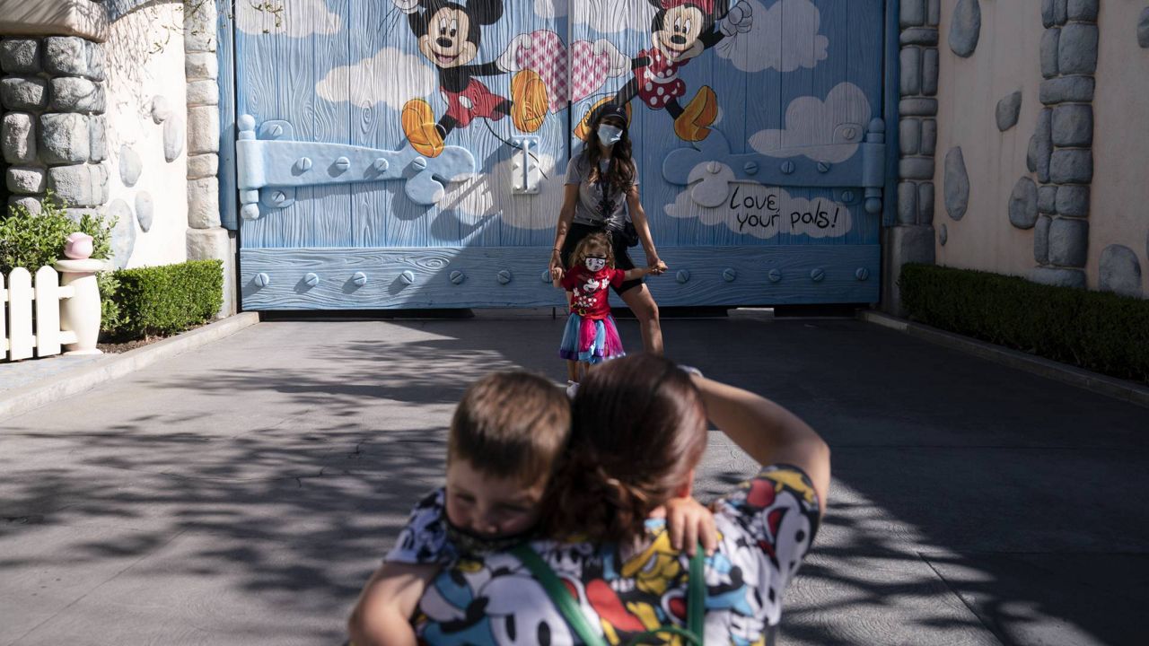 Visitors take pictures at Disneyland in Anaheim, Calif., Friday, April 30, 2021. (AP Photo/Jae C. Hong)