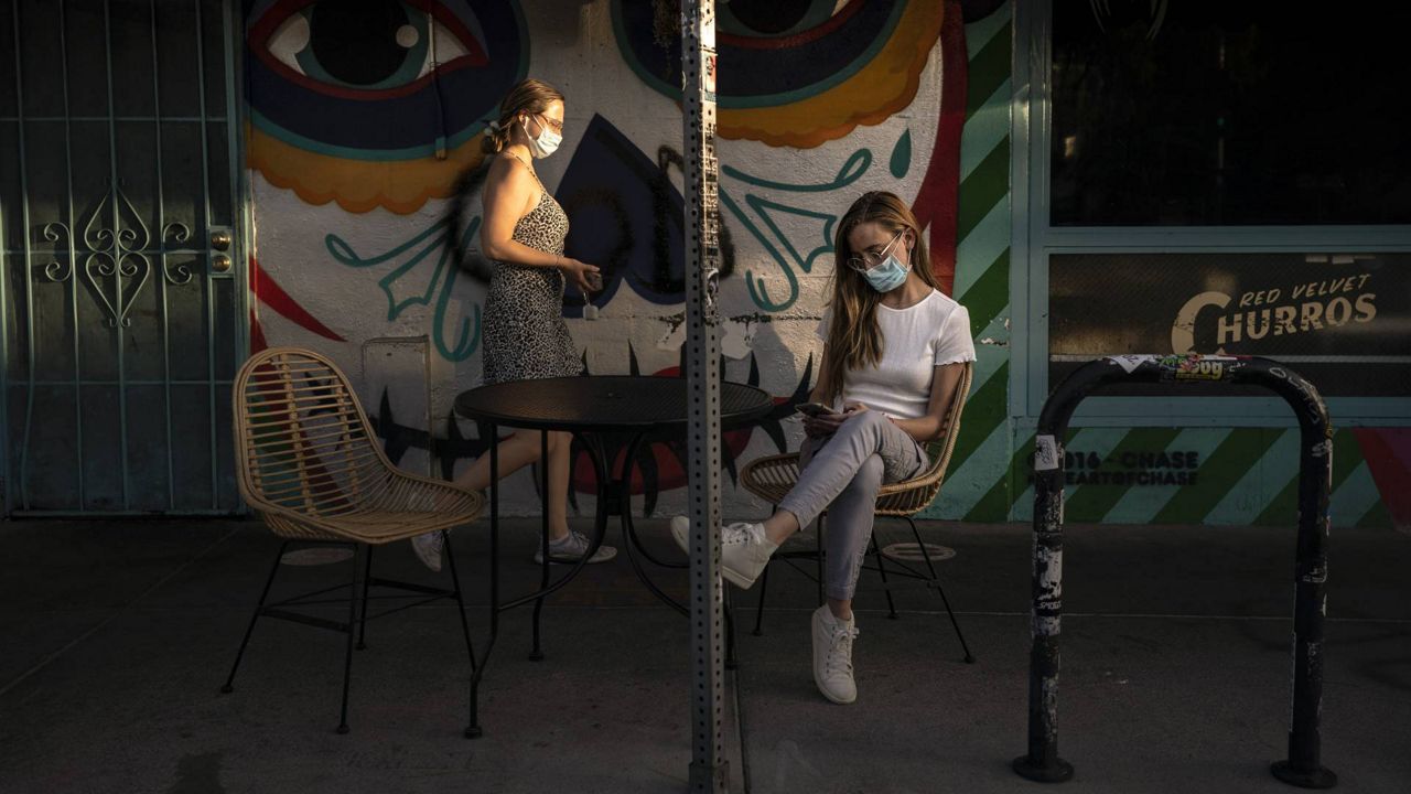 Katherine Stricker, right, waits for her food outside a Mexican restaurant in Los Angeles, May 3, 2021. (AP Photo/Jae C. Hong)