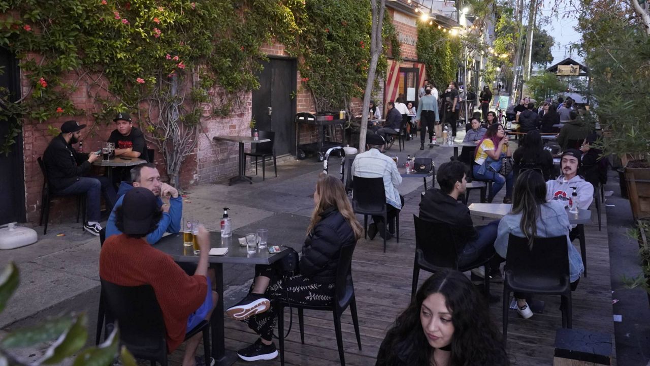 In this May 2, 2021 photo, diners fill the sidewalk tables of Wurstküche, eating sausages and drinking Belgian and German beer in downtown Los Angeles. (AP Photo/Damian Dovarganes)