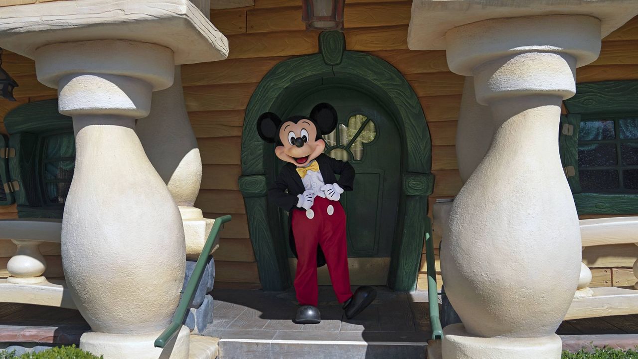 In this Friday, April 30, 2021, file photo, Mickey Mouse keeps social distance while interacting with guests at Disneyland in Anaheim, Calif. (AP Photo/Jae C. Hong, File)