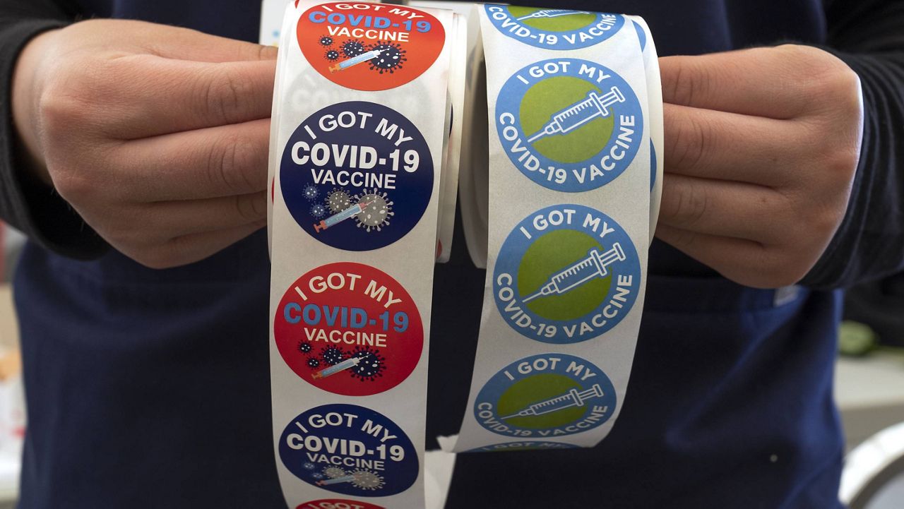 A nurse holds stickers reading "I got my COVID-19 vaccine" at the Mexican Consulate in Los Angeles Saturday, May 8, 2021. (AP Photo/Damian Dovarganes)