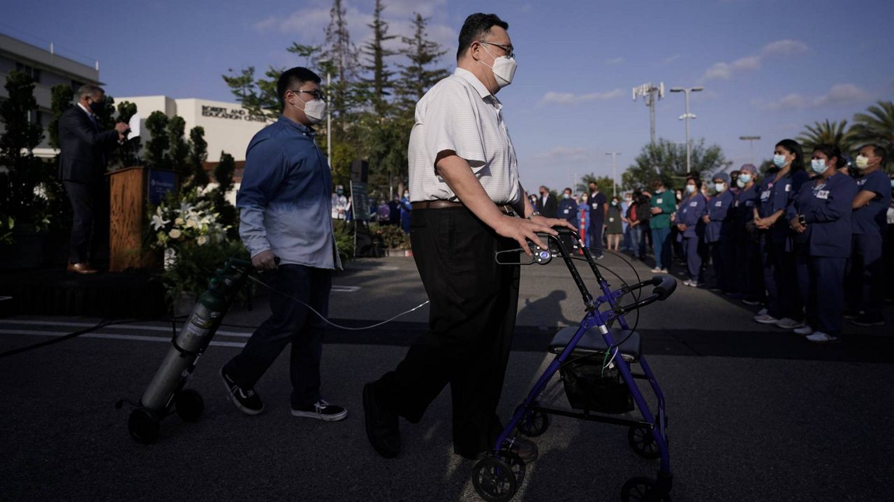 Daniel Kim, center, a former patient who survived COVID-19, and his son Evan walk to join hospital staff members after delivering a speech during an event at Providence St. Jude Medical Center in Fullerton, Calif., May 10, 2021. (AP Photo/Jae C. Hong)