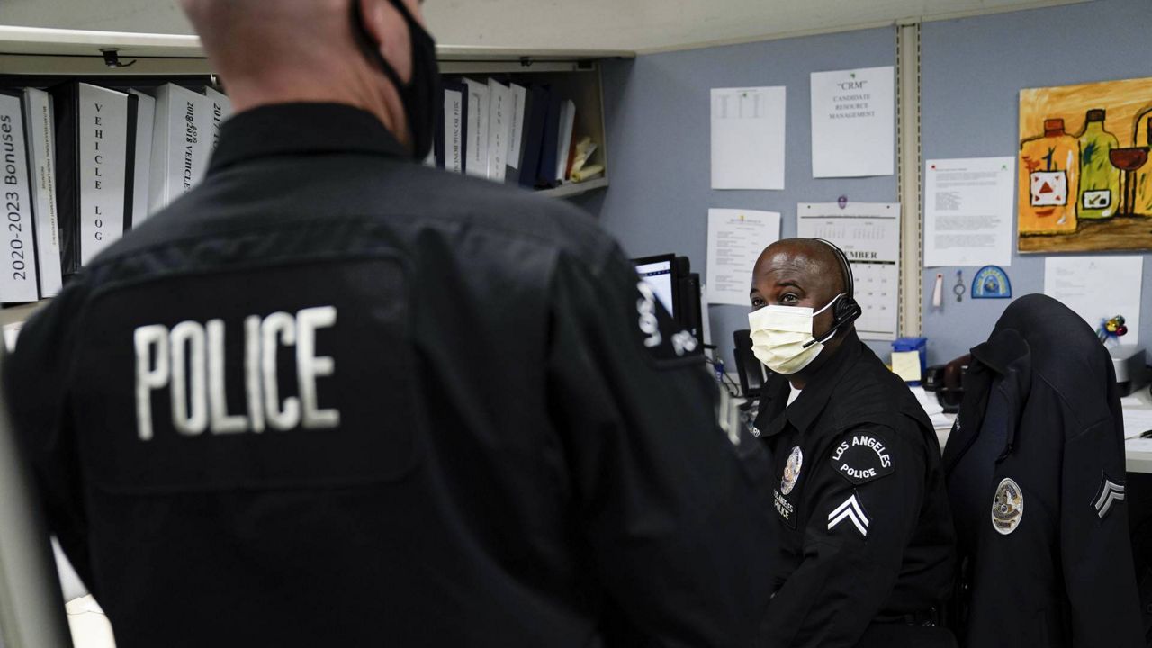 In this Sept. 9, 2020 photo, Los Angeles Police recruitment officers, Dion Gourdine, right, and Christopher Hoffman, chat in the office in Los Angeles. (AP Photo/Jae C. Hong)