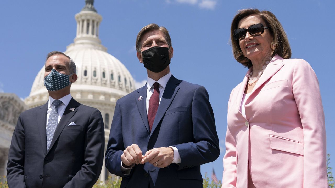 Los Angeles Mayor Eric Garcetti, left, Rep. Greg Stanton, D-Ariz., and House Speaker Nancy Pelosi, D-Calif., right, attends a news conference on infrastructure, Wednesday, May 12, 2021, on Capitol Hill in Washington. (AP Photo/Jacquelyn Martin)