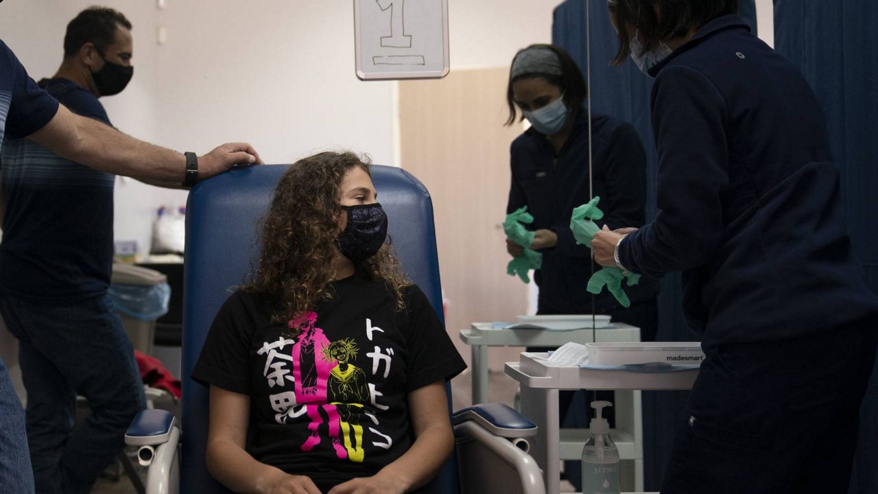 Sarah Jackman, 12, waits to receive the Pfizer COVID-19 vaccine from nurse practitioner Nicole Noche as she is accompanied by her father, Scott, at Families Together of Orange County in Tustin, Calif., May 13, 2021. (AP Photo/Jae C. Hong)
