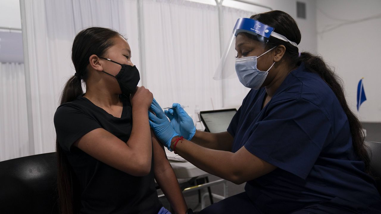 Payton Nguyen, 12, receives the Pfizer COVID-19 vaccine from nurse Lakera Thorne at Providence Edwards Lifesciences vaccination site in Santa Ana, Calif., Thursday, May 13, 2021. The state began vaccinating children ages 12 to 15 Thursday.(AP Photo/Jae C. Hong)