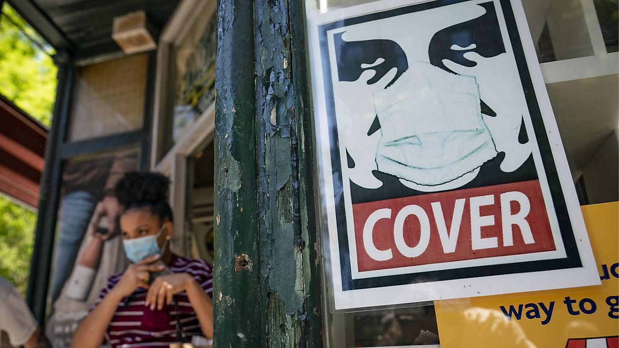 A customer exits a corner market Friday while wearing a mask in New York City's SoHo neighborhood. (AP Photo/John Minchillo)