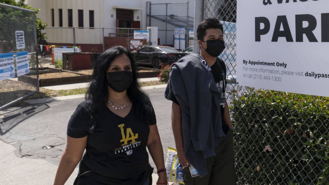 In this April 15, 2021 file photo, parent Rosa Vargas and her son Victor Loredo, 14, walk home after getting tested at an LAUSD COVID-19 testing and vaccination site in East LA. (AP Photo/Damian Dovarganes)