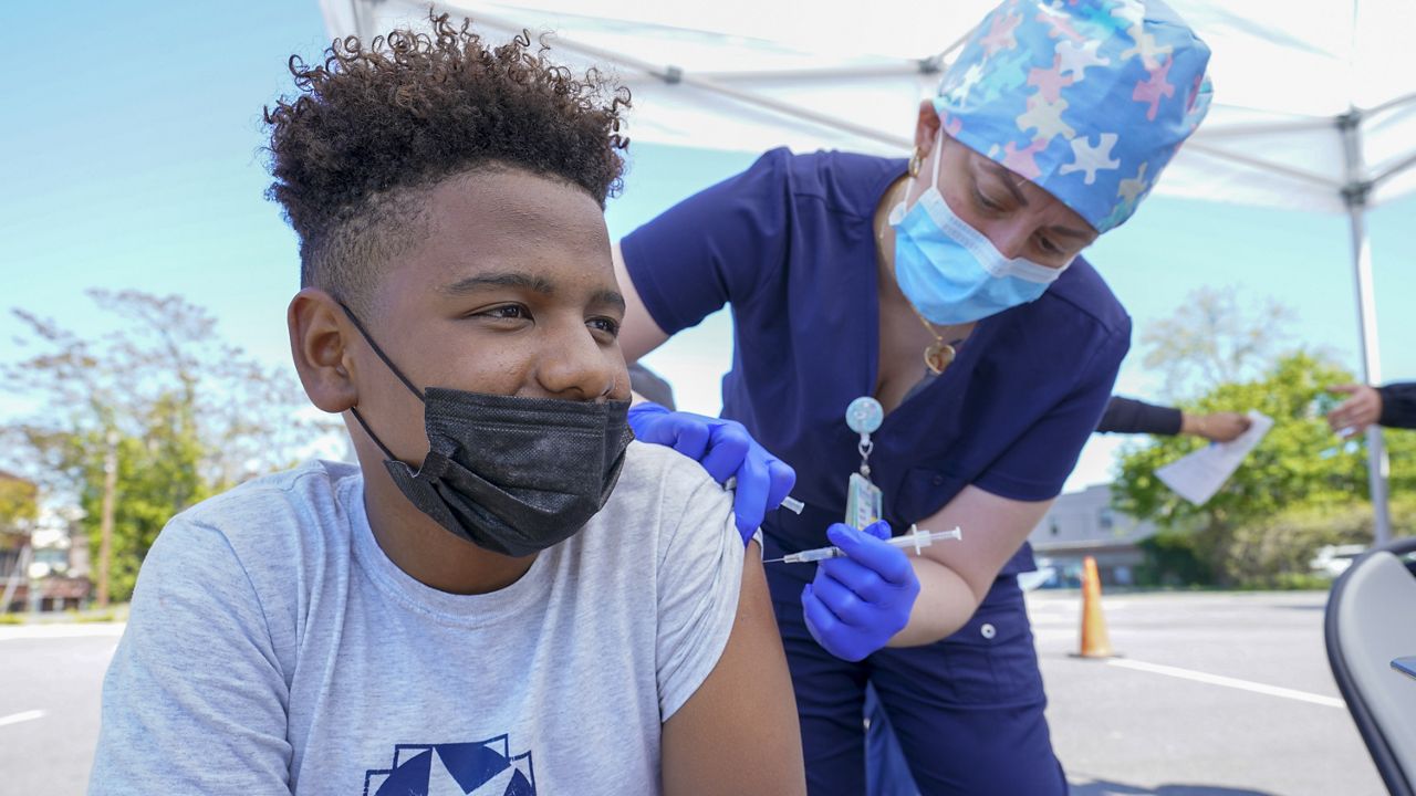 Registered Nurse Jennifer Reyes inoculates Wilson Moro, 12, with the first dose of the Pfizer COVID-19 vaccine at the Mount Sinai South Nassau Vaxmobile parked at the De La Salle School, Friday, May 14, 2021, in Freeport, N.Y. (AP Photo/Mary Altaffer)