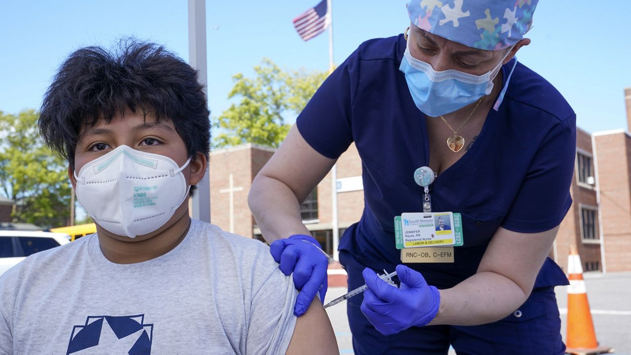 Registered Nurse Jennifer Reyes inoculates Andres Clara, 12, with the first dose of the Pfizer COVID-19 vaccine at the Mount Sinai South Nassau Vaxmobile parked at the De La Salle School, Friday, May 14, 2021, in Freeport, N.Y. (AP Photo/Mary Altaffer)