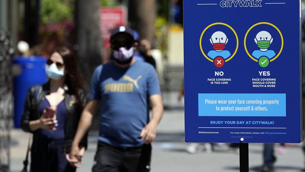 Signs instruct visitors on the proper way to wear masks at the Universal City Walk Friday, May 14, 2021, in Universal City, Calif. (AP Photo/Marcio Jose Sanchez)