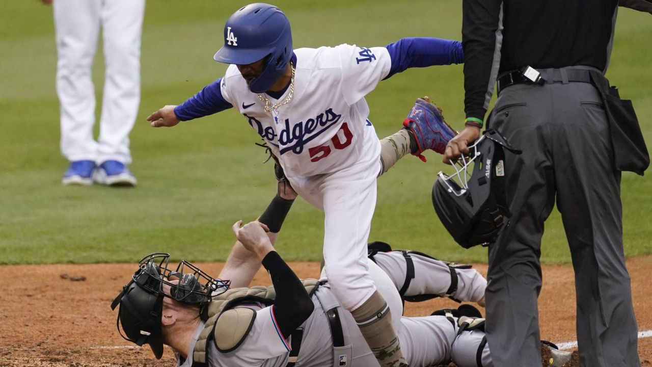 Miami Marlins catcher Chad Wallach, bottom, tags out Dodgers' Mookie Betts (50) at home during the fifth inning Sunday, May 16, 2021, in Los Angeles. (AP Photo/Ashley Landis)
