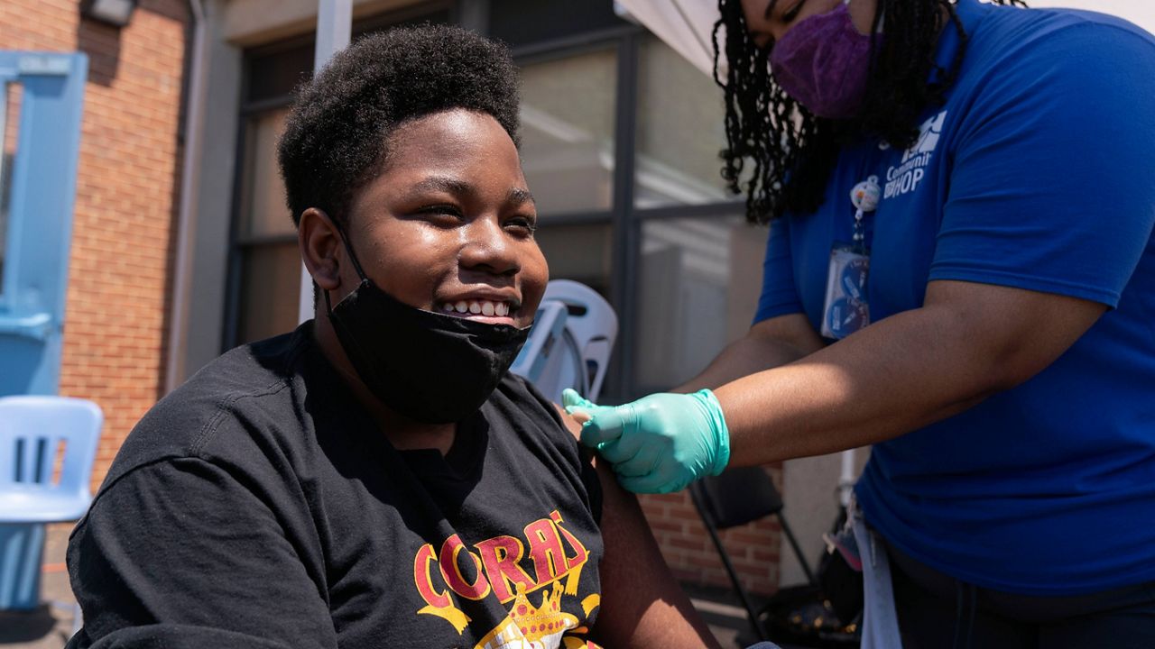 Christopher Fitzhugh, 13, of Washington, D.C., laughs in relief on May 19 that his Pfizer COVID-19 vaccine shot didn't hurt. (AP Photo/Jacquelyn Martin, File)