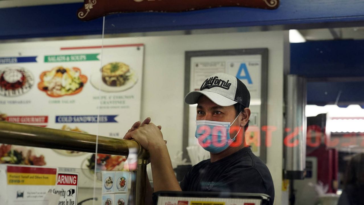 A worker wears a mask while waiting to take orders in a deli amid the COVID-19 pandemic Thursday, May 20, 2021, at The Farmers' Market in Los Angeles. (AP Photo/Marcio Jose Sanchez)