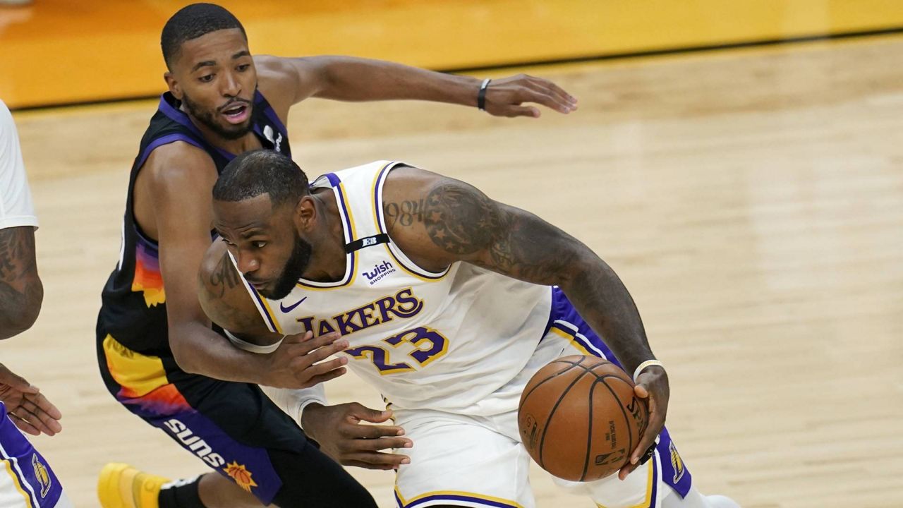 Lakers forward LeBron James drives past Phoenix Suns forward Mikal Bridges, left, during Game 1 of an NBA first-round playoff series Sunday, May 23, 2021, in Phoenix. (AP Photo/Ross D. Franklin)