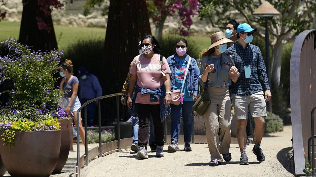 In this May 26, 2021, file photo, visitors wear masks while walking the garden at the newly re-opened Getty Center amid the COVID-19 pandemic in Los Angeles. (AP Photo/Marcio Jose Sanchez)