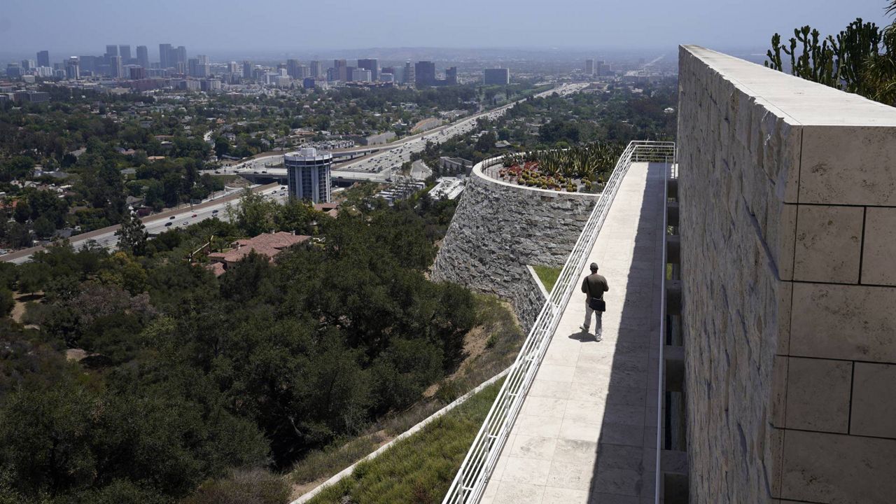 A visitor strolls along a walkway overlooking the city at the newly re-opened Getty Center amid the COVID-19 pandemic, May 26, 2021, in Los Angeles. (AP Photo/Marcio Jose Sanchez)